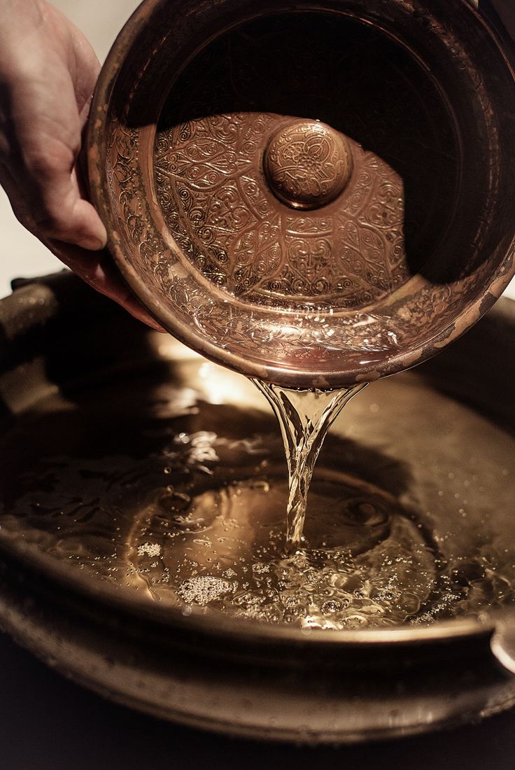 Water poured from an engraved copper bowl during a Moroccan bathing ritual